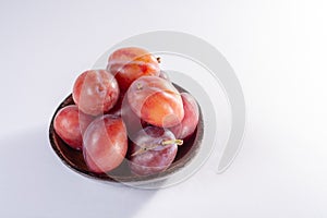 Group of ripe oval Victoria plums from England on white background with leaves