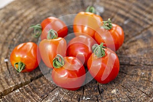 Group of ripened tasty red raw strawberry tomatoes on wood on green natural background, tasty healthy vegetables still life