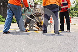 Group of road worker paint traffic lines on asphalt road surface.