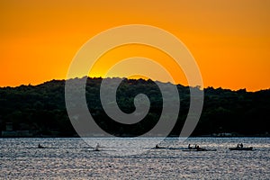 Group of Rowers on Water at Sunset