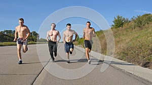 Group of runners men jogging at highway. Male sport athletes training outdoor at summer. Young strong muscular guys