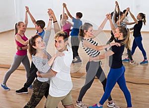 Group of satisfied teenagers dancing tango in dance studio