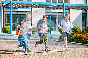 Group of school children with backpacks run out of school, after the end of classes