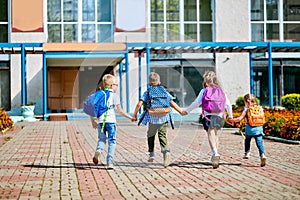 Group of school children with backpacks run out of school, after the end of classes