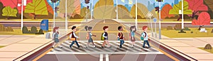 Group Of School Children Crossing Road On Crosswalk With Traffic Lights