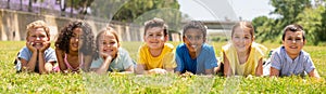 Group of school children resting on grass and smiling