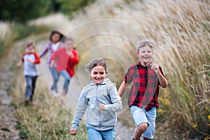 Group of school children running on field trip in nature.