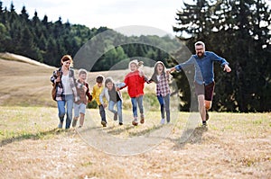 Group of school children with teacher on field trip in nature, running.