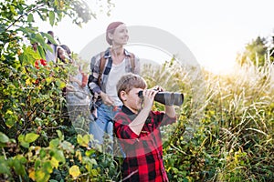 Group of school children with teacher on field trip in nature, using binoculars.