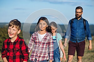 Group of school children with teacher on field trip in nature, walking.