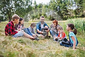 Group of school children with teacher and windmill model on field trip in nature.