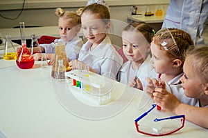 Group of school girl kids with teacher in school laboratory making experiment observing the chemical reaction with the
