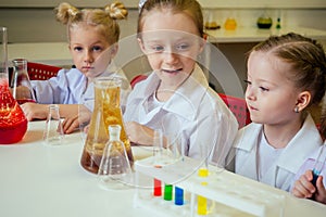 Group of school girl kids with teacher in school laboratory making experiment observing the chemical reaction with the