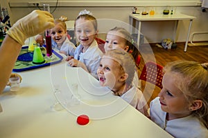 Group of school girl kids with teacher in school laboratory making experiment observing the chemical reaction with the