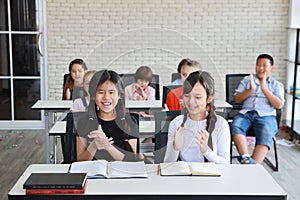 Group of school kids clapping hands in classroom education concept