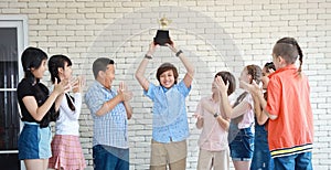 Group of school kids holding trophy with happy smiling face in classroom on white wall education concept