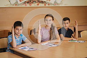 Group of school kids with pens and notebooks writing test in classroom. education, elementary school, learning and