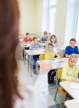 Group of school kids raising hands in classroom