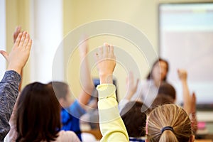 Group of school kids raising hands in classroom