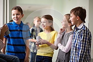 Group of school kids with soda cans in corridor