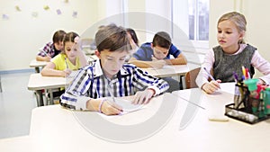 Group of school kids writing test in classroom