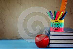 Group of school supplies and books and red apple over on backgro