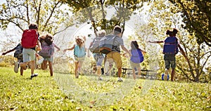 Group of schoolchildren running in a field, back view