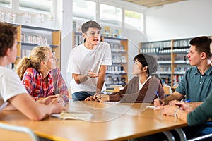 Group of schoolchildren in the school library, discussing something