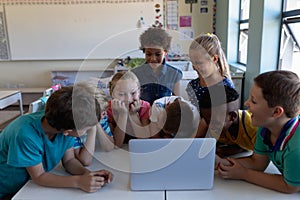Group of schoolchildren using a laptop computer in an elementary school classroom