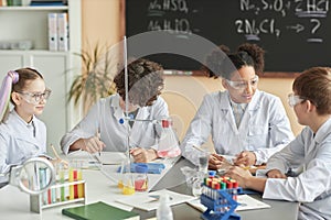 Group of schoolchildren wearing lab coats during science experiment class