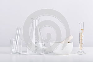 Group of scientific laboratory glassware and mortar with clear liquid solution, Research