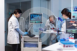 Group of scientists doing research and experiments at medical lab against disease with special equipment