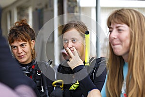 Group of scuba divers on the beach listening to instructions before the dive. female divers in dive gear smile and laugh
