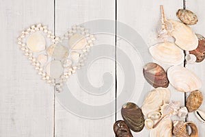 group of sea shells and pearls laid out in the shape of heart on white wooden background