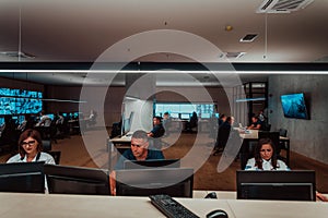 Group of Security data center operators working in a CCTV monitoring room looking on multiple monitors Officers