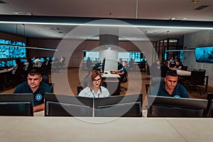 Group of Security data center operators working in a CCTV monitoring room looking on multiple monitors Officers