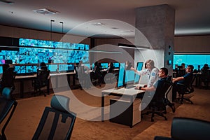 Group of Security data center operators working in a CCTV monitoring room looking on multiple monitors Officers