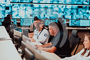 Group of Security data center operators working in a CCTV monitoring room looking on multiple monitors Officers