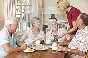 Group Of Senior Couples Enjoying Afternoon Tea Together At Home With Home Help