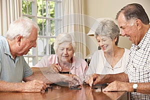 Group Of Senior Couples Enjoying Game Of Dominoes At Home