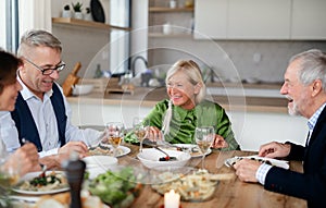 Group of senior friends at dinner party at home, eating.