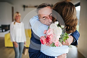 Group of senior friends at dinner party at home, greeting.