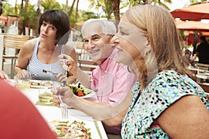 Group Of Senior Friends Enjoying Meal In Outdoor Restaurant
