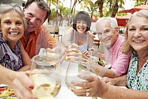 Group Of Senior Friends Enjoying Meal In Outdoor Restaurant