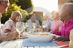 Group Of Senior Friends Enjoying Outdoor Dinner Party At Home