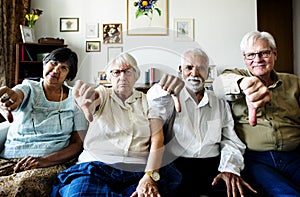 Group of senior friends gesturing thumbs down sign photo