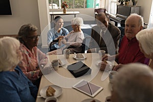 Group of senior friends having breakfast on dining table at nursing home