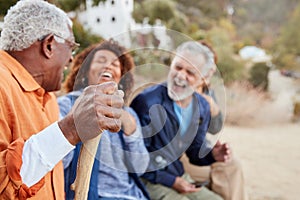 Group Of Senior Friends On Hike In Countryside Looking At Mobiles Phones Together