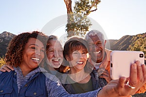 Group Of Senior Friends Posing For Selfie As They Hike Along Trail In Countryside Together photo