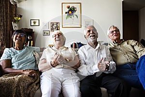 Group of senior friends sitting and watching tv together photo